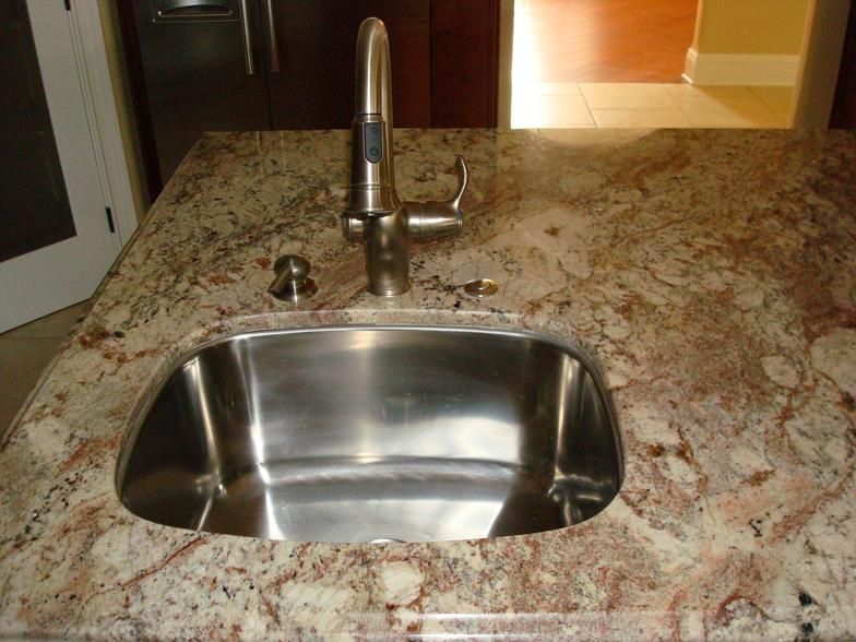 Stainless steel kitchen sink with faucet on a granite countertop.