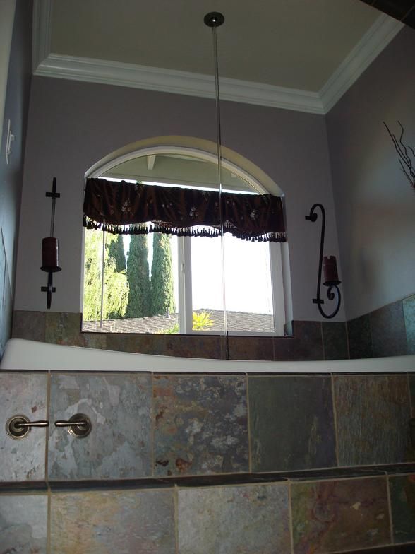 Bathroom with arch window, slate tile tub surround, and purple walls. 