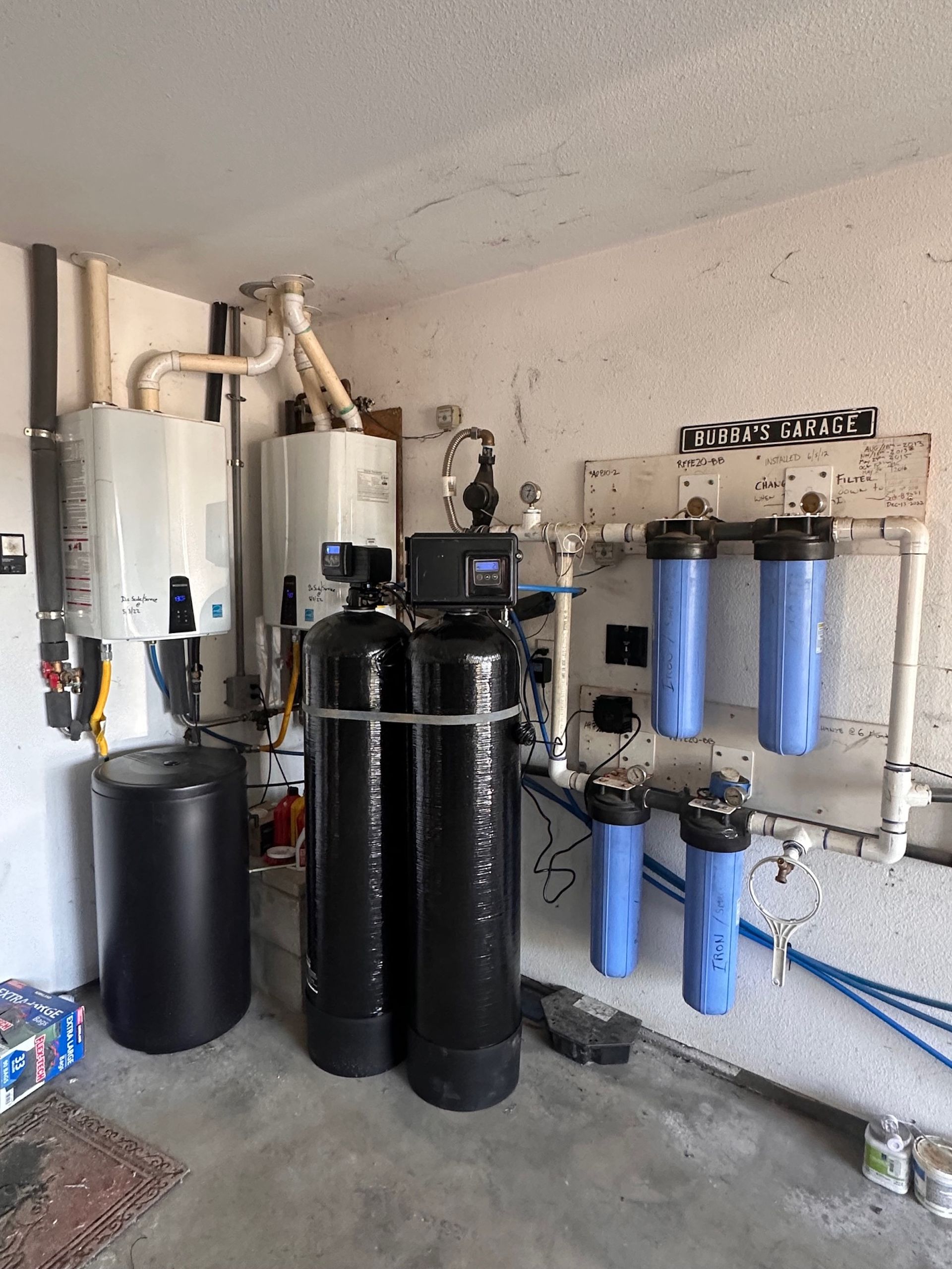Water treatment system in a garage with tanks, filters, and piping.