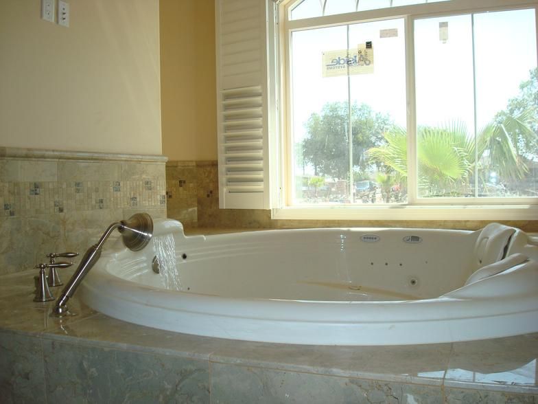 A white jacuzzi bathtub in a bathroom, next to a large window overlooking greenery.