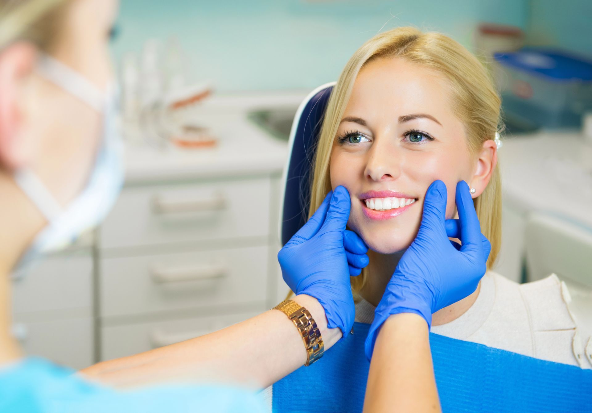 Un dentista con i guanti blu esamina il sorriso di un paziente in uno studio dentistico.