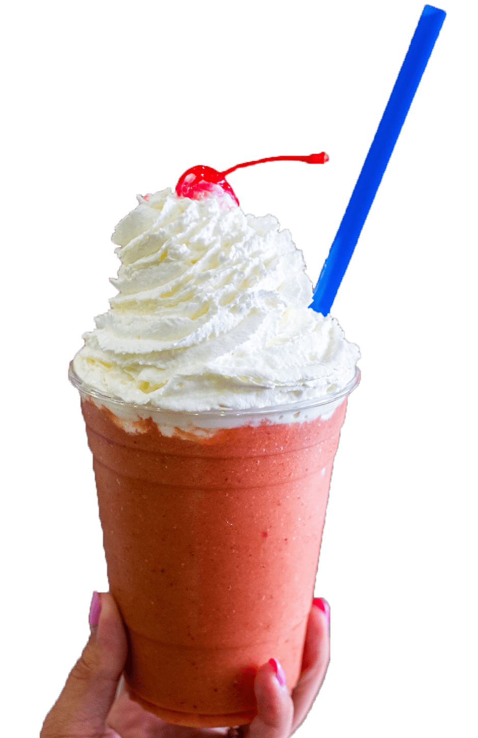 A hand holding a coral-colored smoothie in a clear cup, topped with whipped cream, a cherry, and a blue straw.