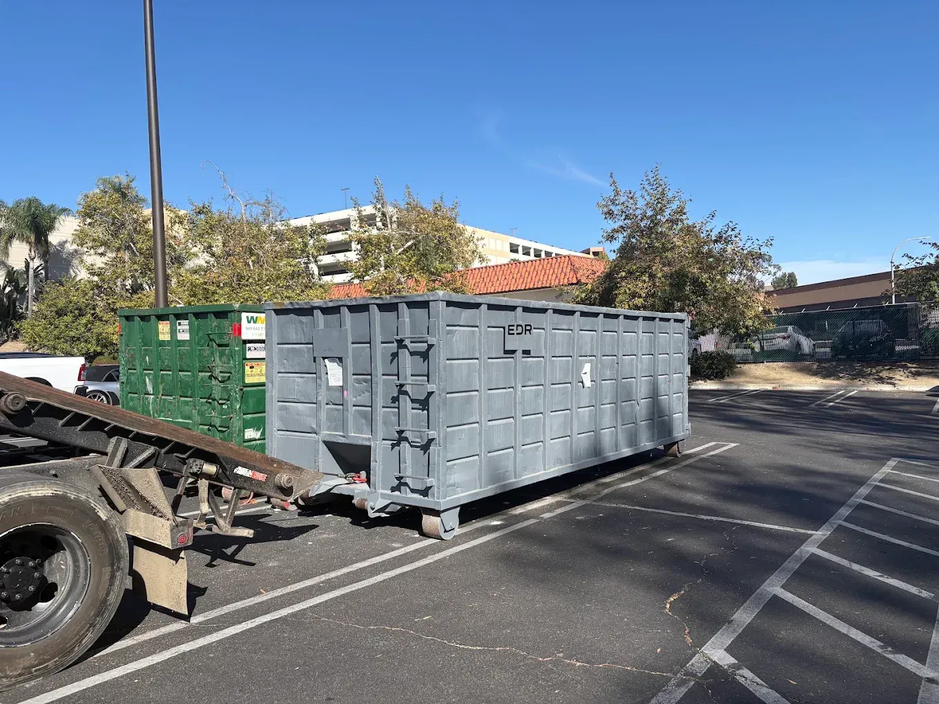 A black dumpster is sitting on top of a white surface.