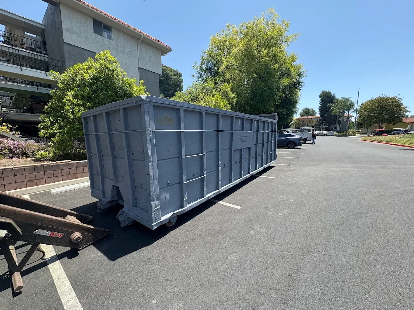 A black dumpster is sitting on top of a white surface.
