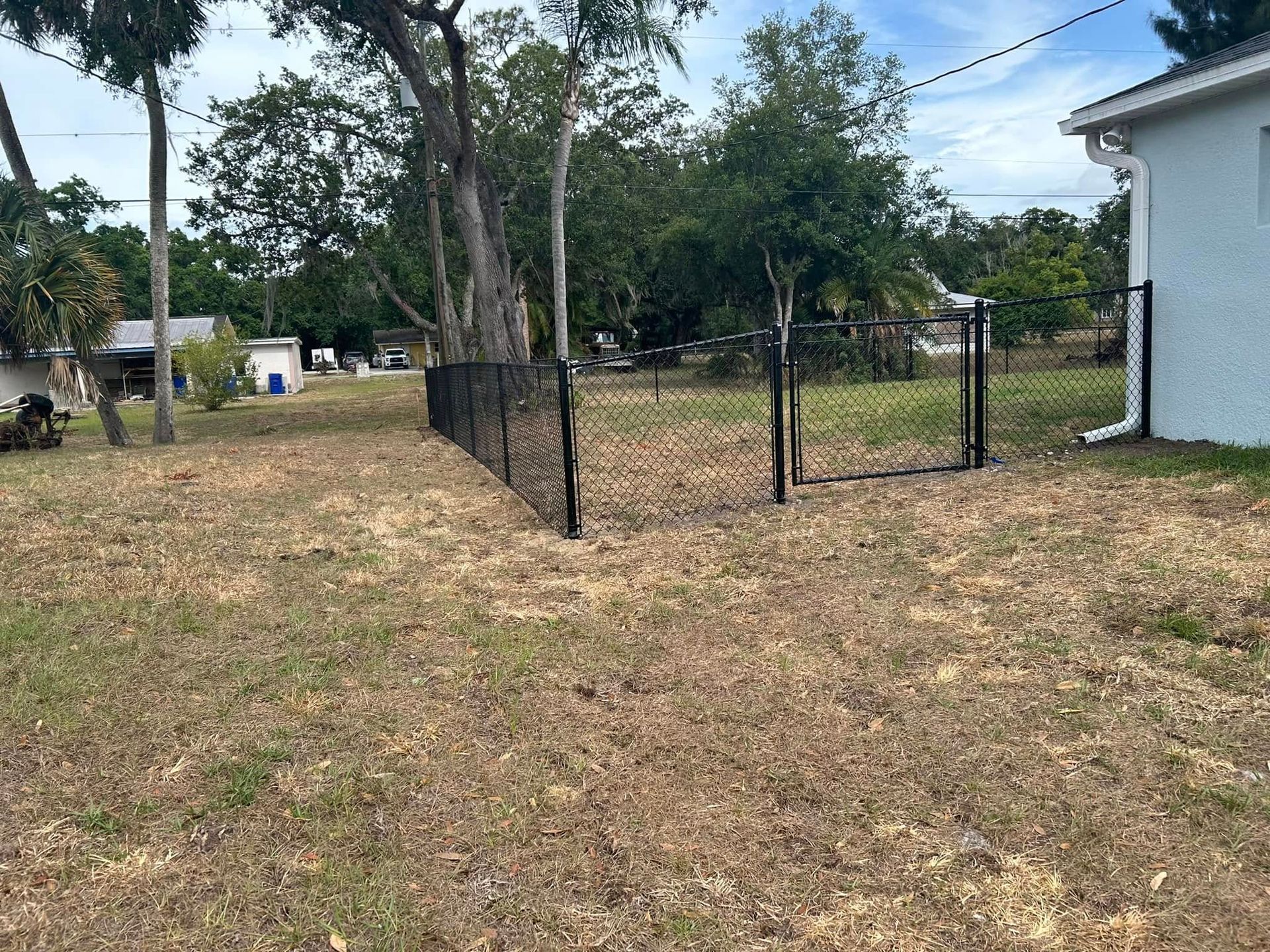 There is a chain link fence in the backyard of a house.