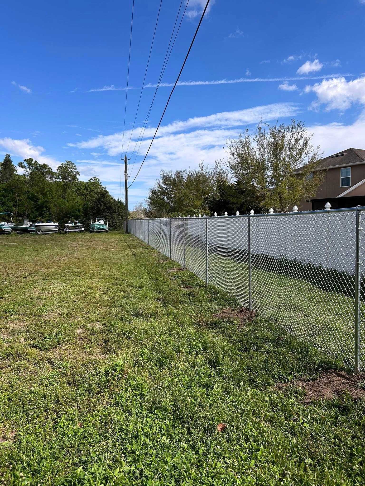 A chain link fence is surrounding a grassy field.