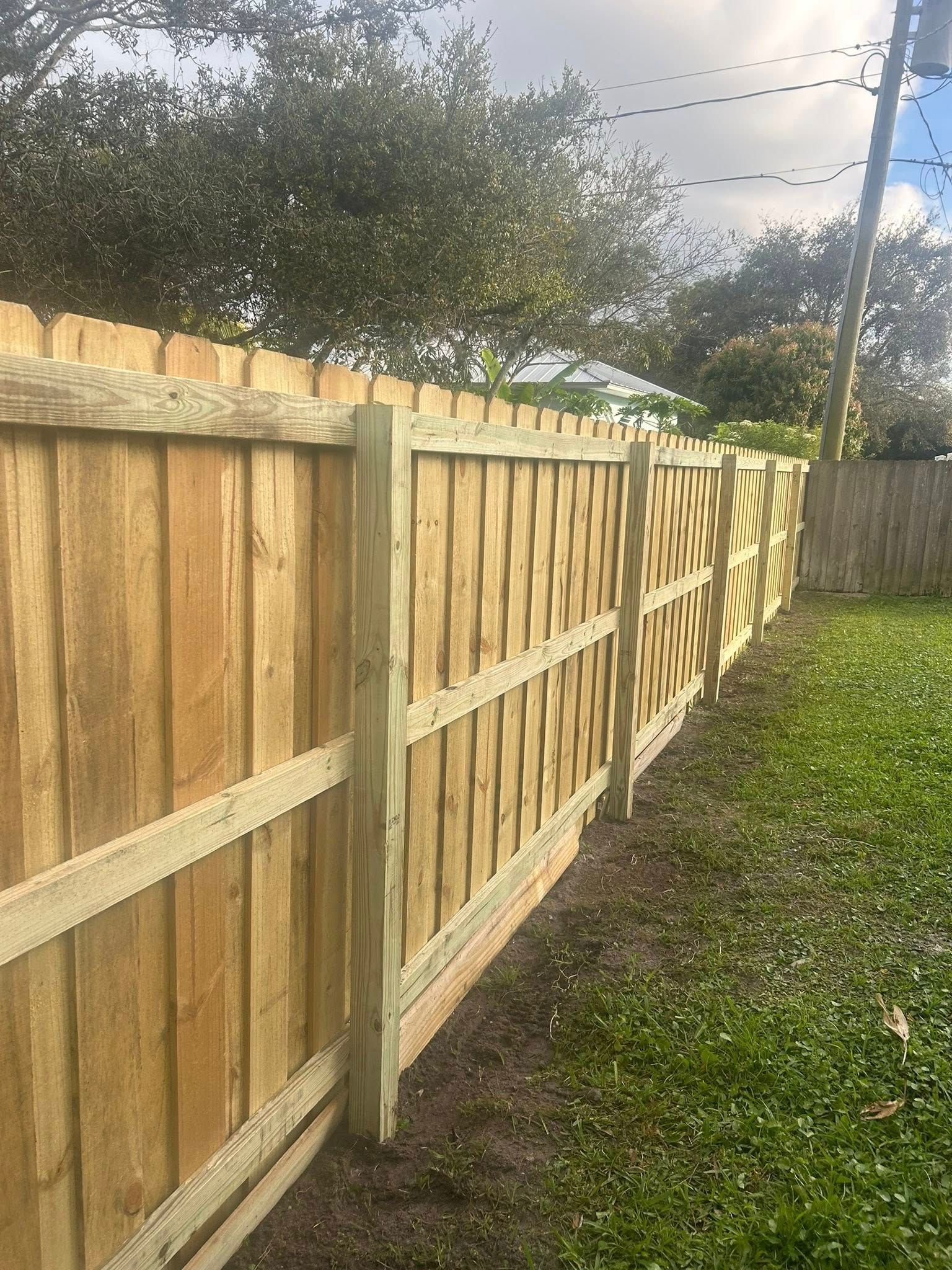 A wooden fence is sitting in the middle of a lush green yard.