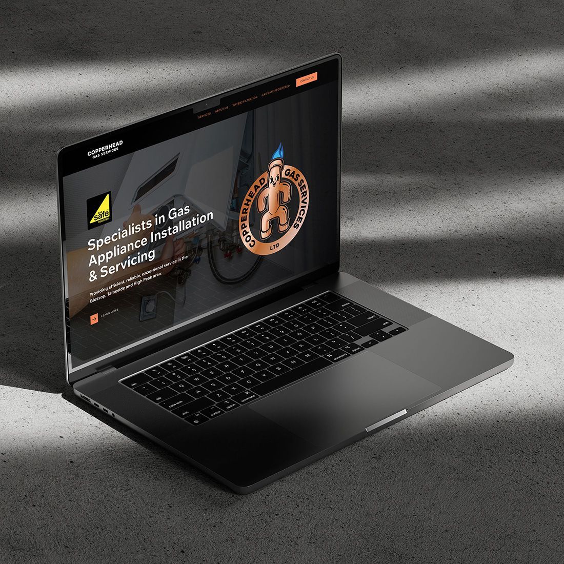 Laptop displaying a website for a gas appliance specialist. The site has a logo and text on a dark background.