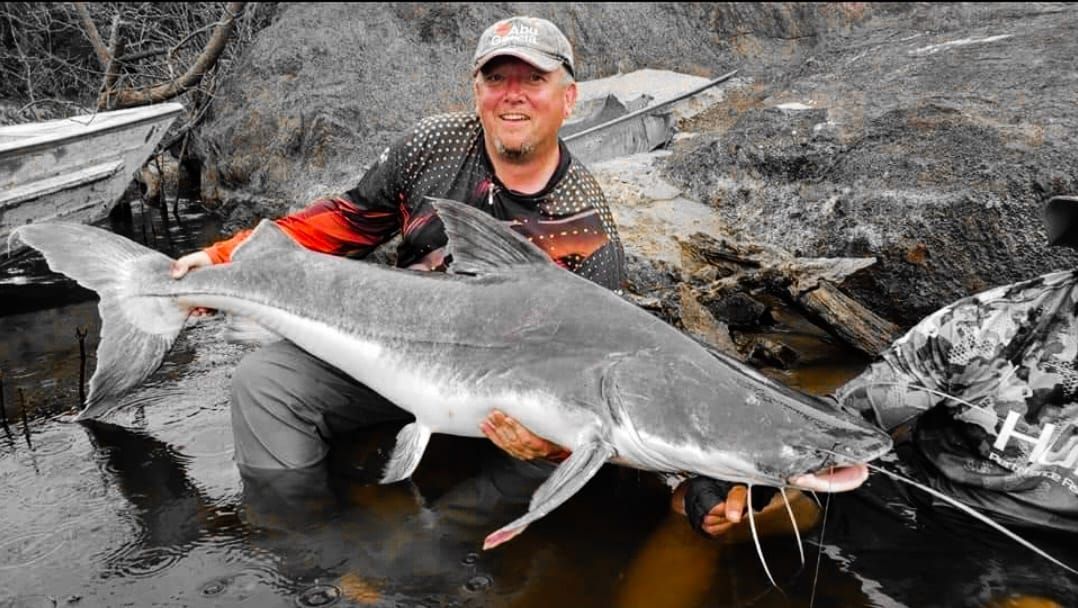 Angler posing with giant Amazon River catfish during Suriname expedition