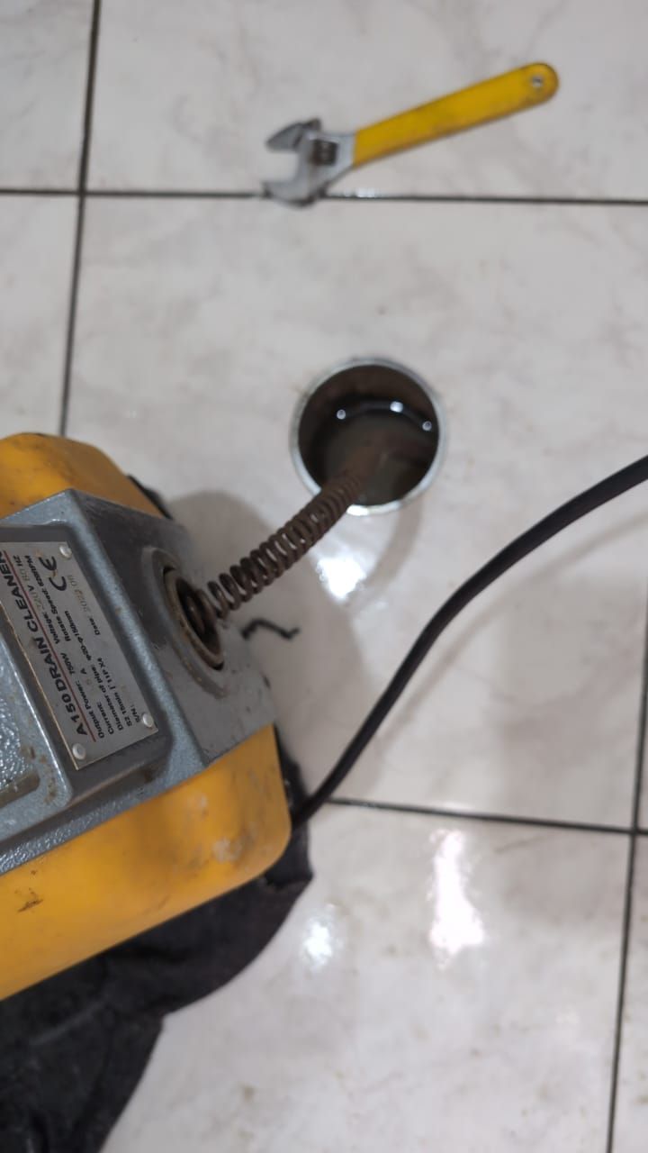 Una máquina amarilla sobre un suelo de baldosas blancas, junto a un pequeño cuenco negro 
