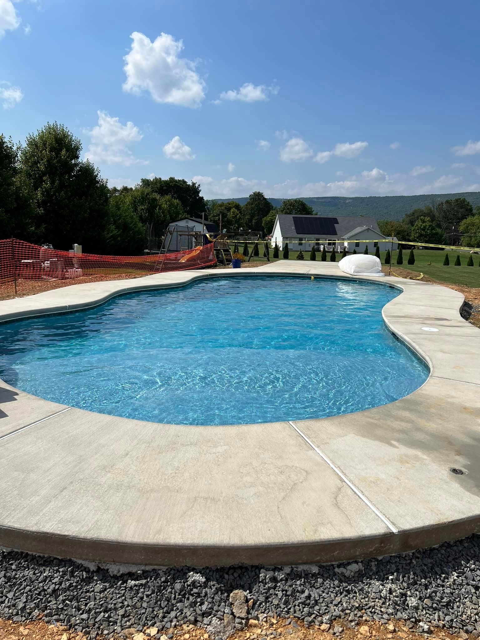 a large swimming pool is being built in the backyard of a house .