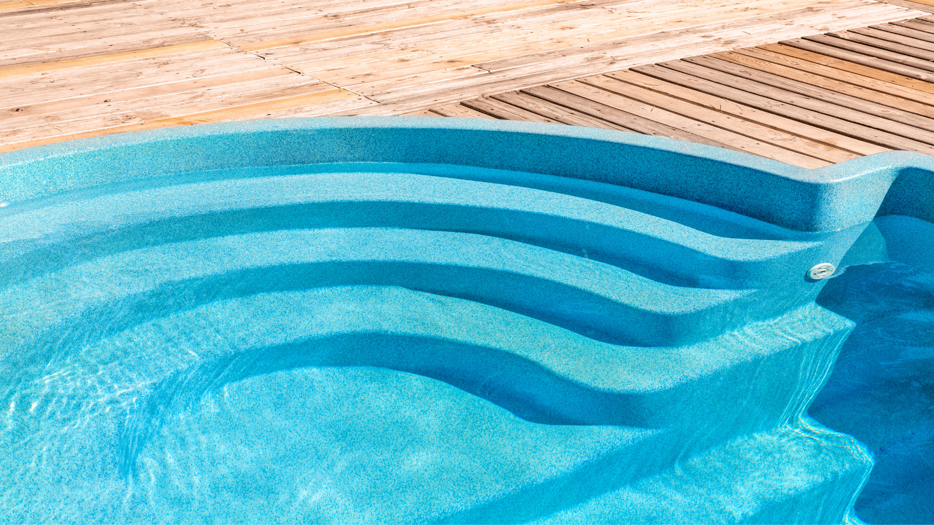a swimming pool with stairs leading up to it and a wooden deck .