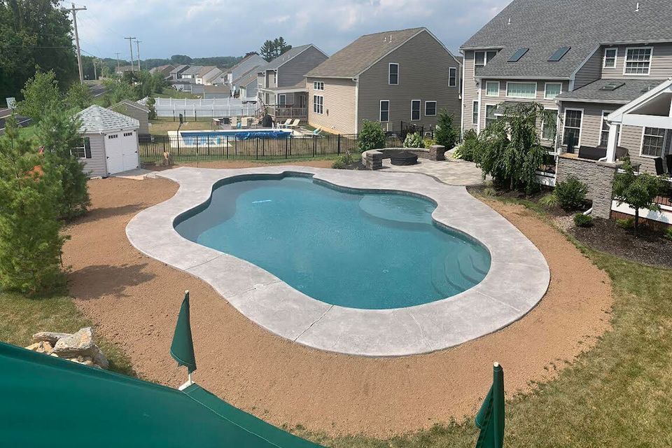 a large swimming pool is in the backyard of a house .