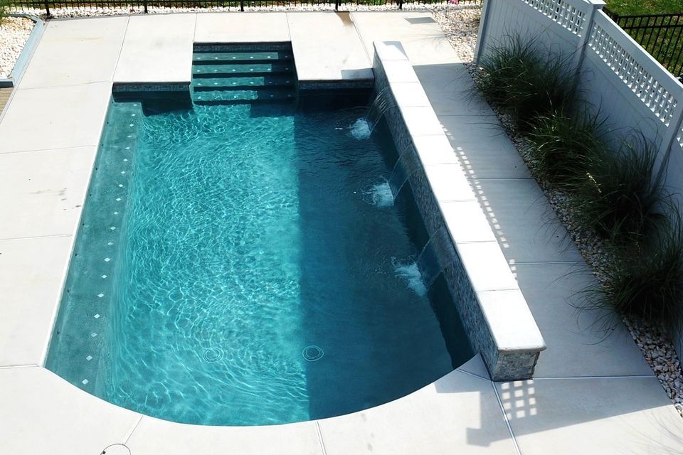 a small swimming pool with stairs and a white fence
