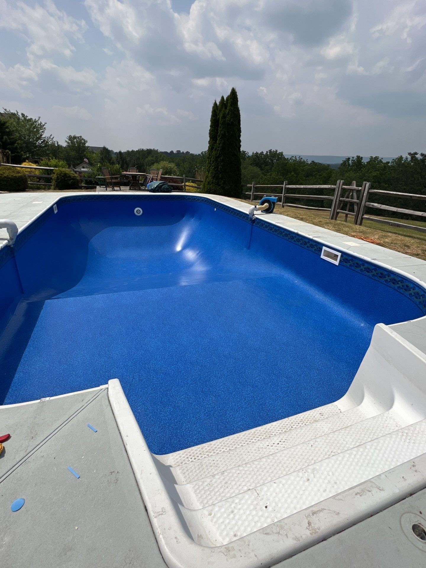 a large blue swimming pool is sitting on top of a concrete deck .