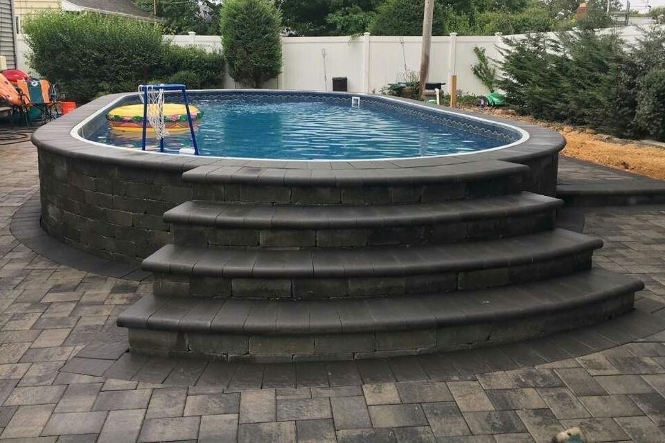 a swimming pool with stairs leading up to it in a backyard .