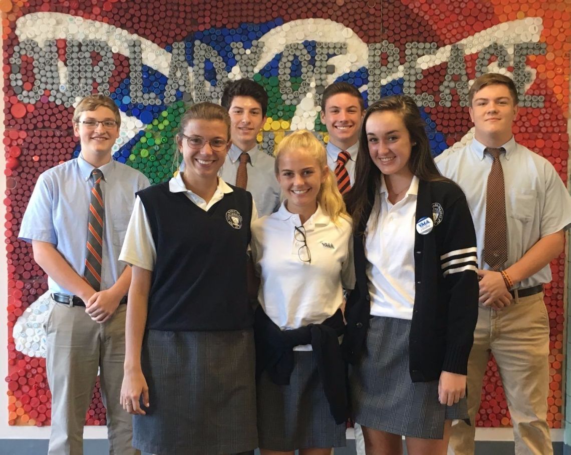 A group of people standing in front of a wall that says world of peace