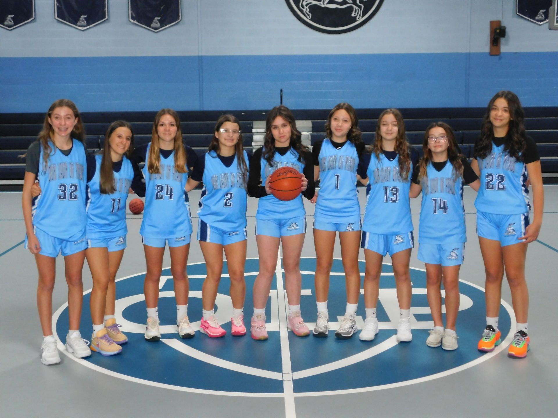 A group of girls are posing for a picture on a basketball court