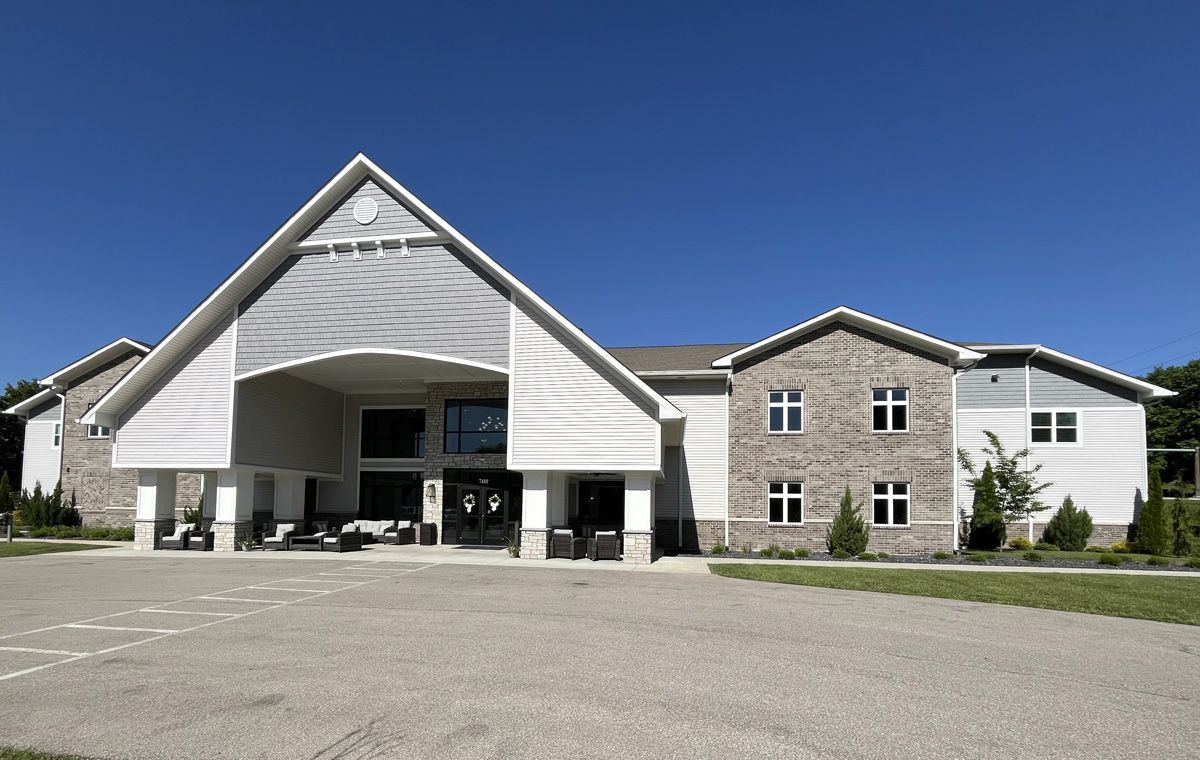Large modern building with a peaked entrance and stone facade under a clear blue sky