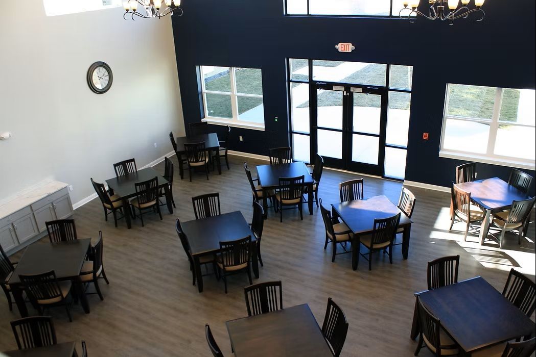 Empty café seating area with black tables and chairs by large front windows and glass doors