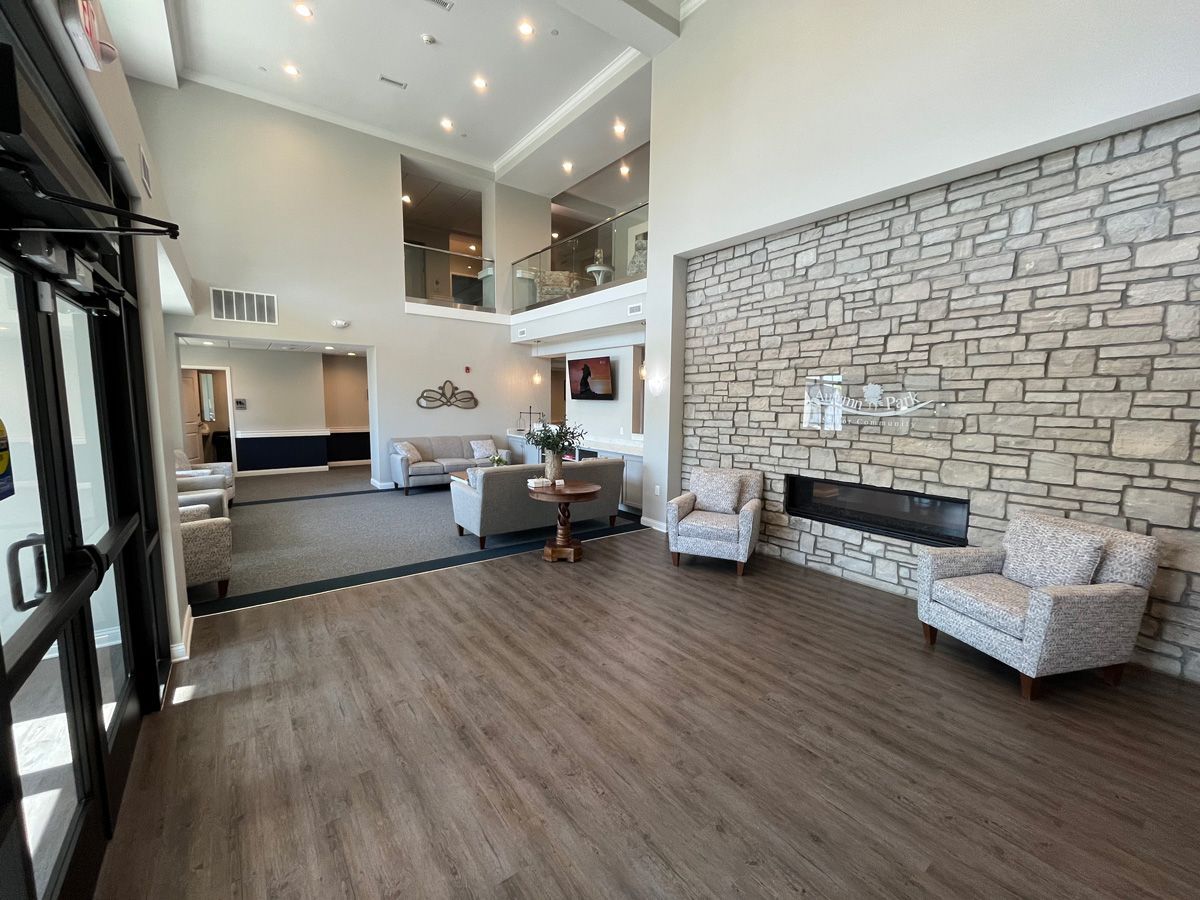 Modern lobby with high ceilings, stone fireplace, lounge chairs, and wood flooring in a bright open space
