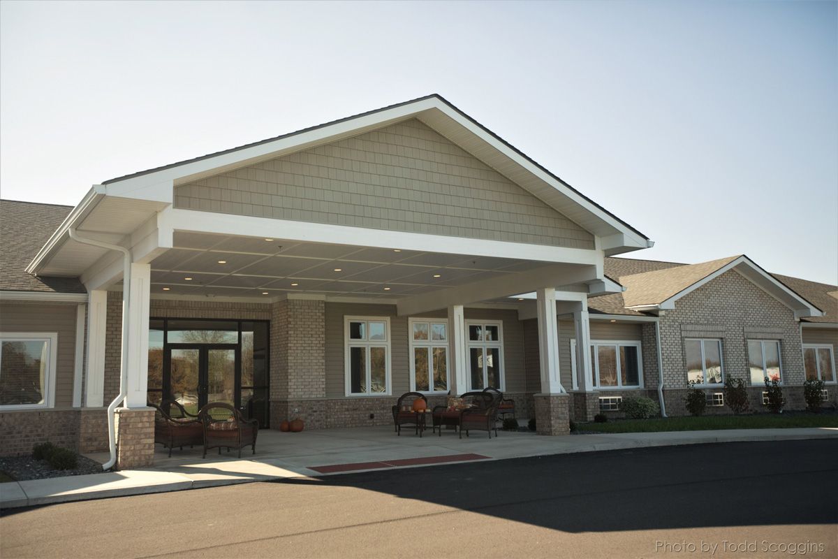 Covered entrance of a beige brick building with columns, windows, and parked bicycles in front