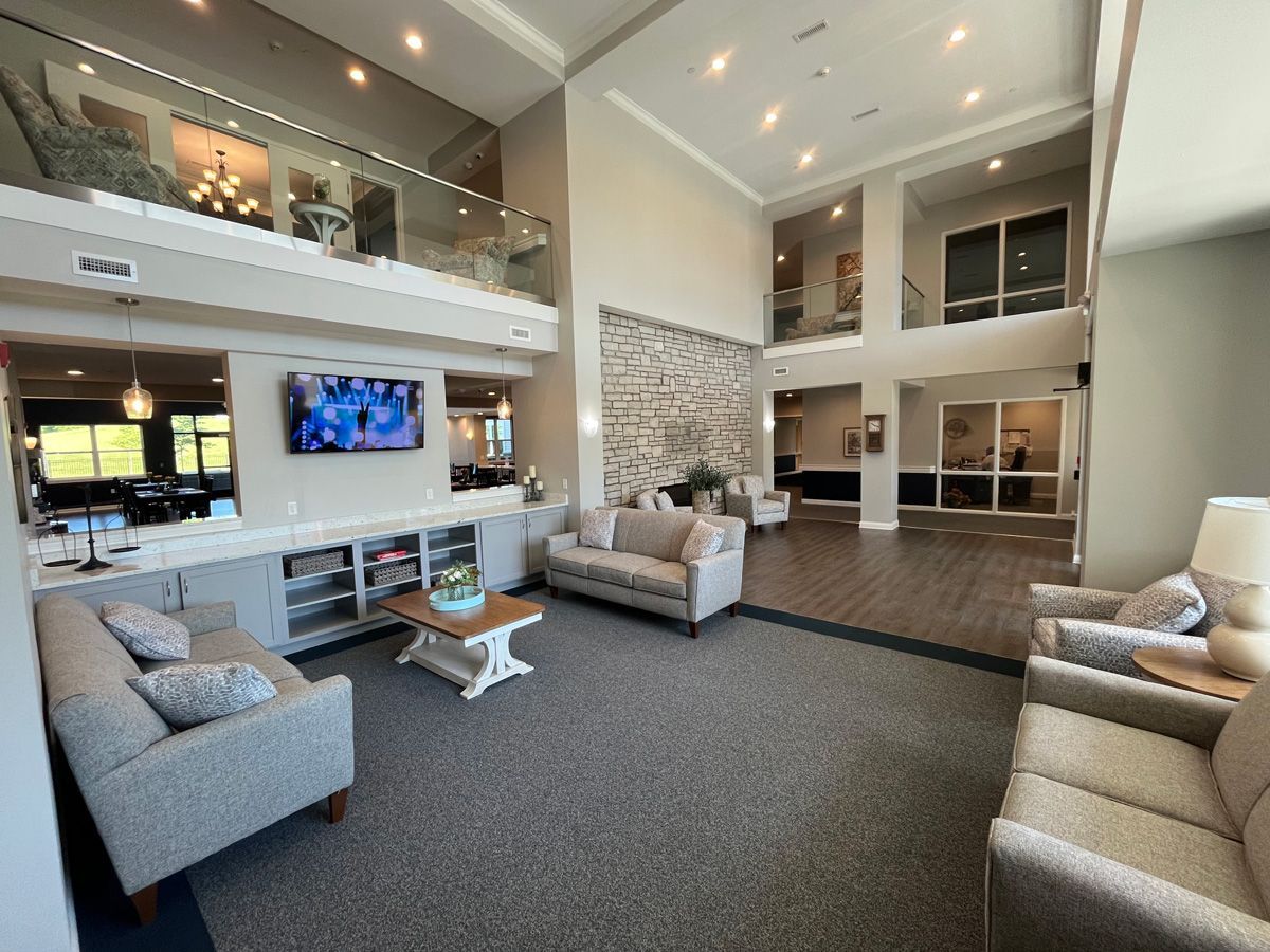 Modern living room with gray sofas, high ceilings, fireplace, and wall-mounted TV in a bright open interior