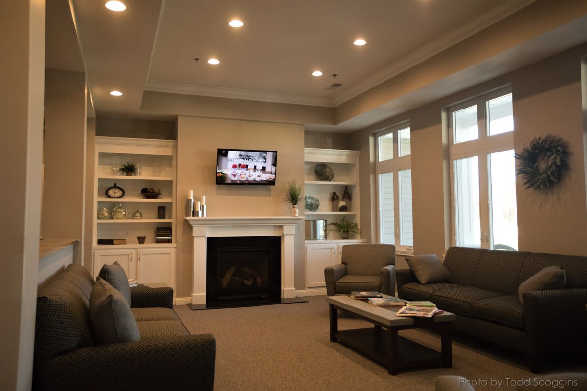 Cozy living room with fireplace, wall-mounted TV, sofas, coffee table, and large windows.