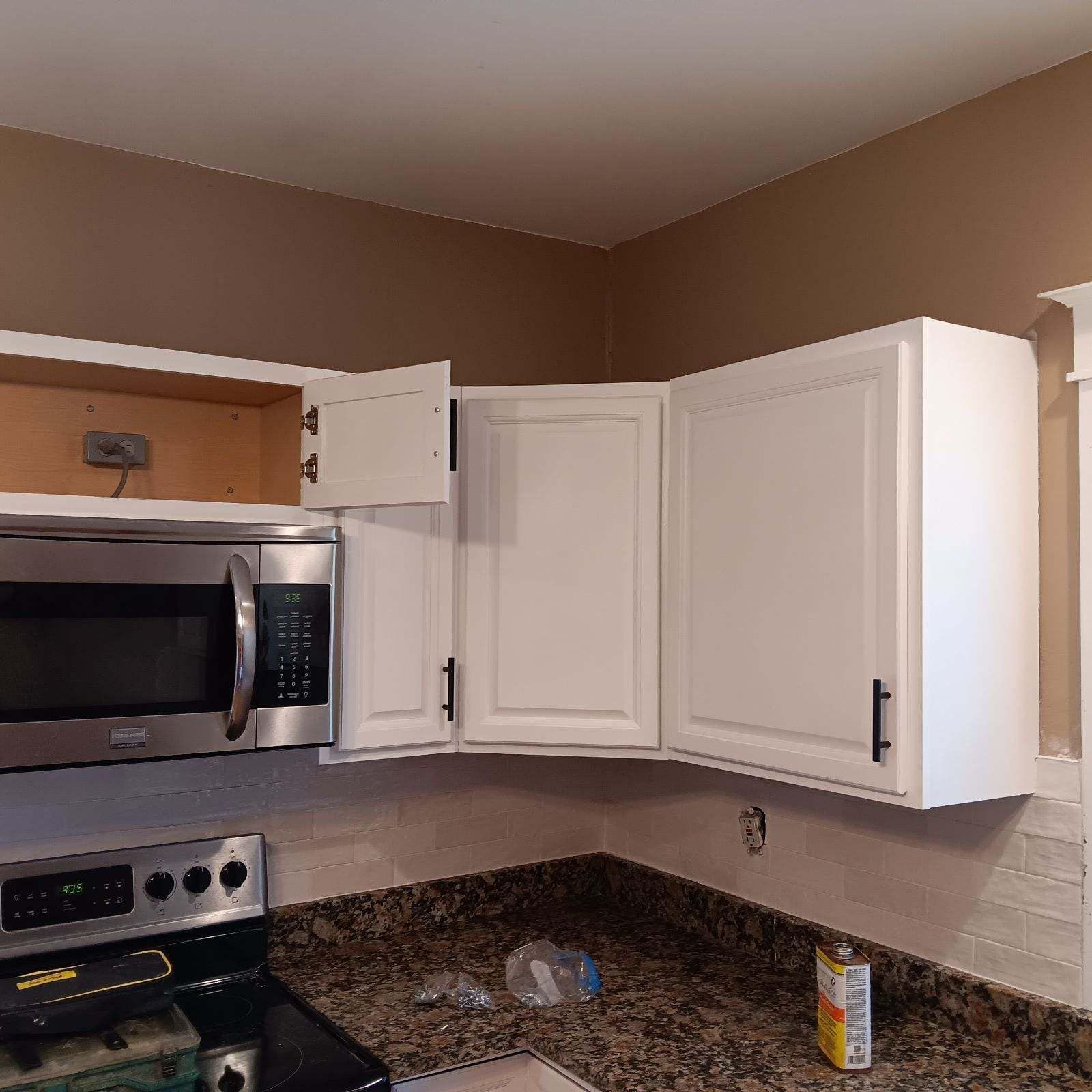 Kitchen cabinets: white, open upper cabinet above a microwave, near a stove and countertop. Kitchen cabinets: white, open upper cabinet above a microwave, near a stove and countertop.