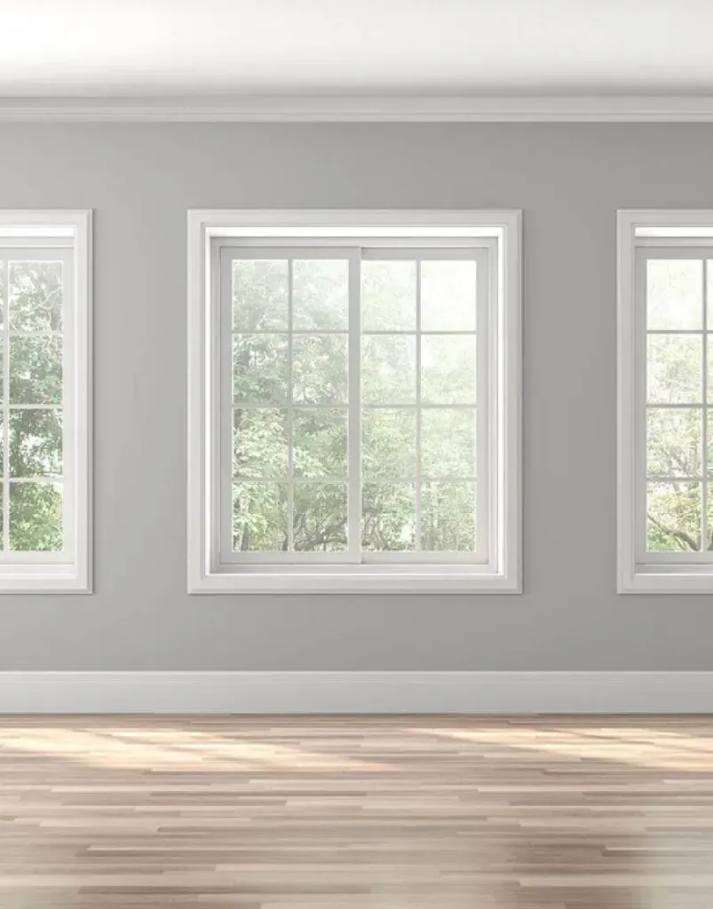 Three white-framed windows on a gray wall. Wooden floor and white trim. Bright light shines through the windows. Three white-framed windows on a gray wall. Wooden floor and white trim. Bright light shines through the windows.