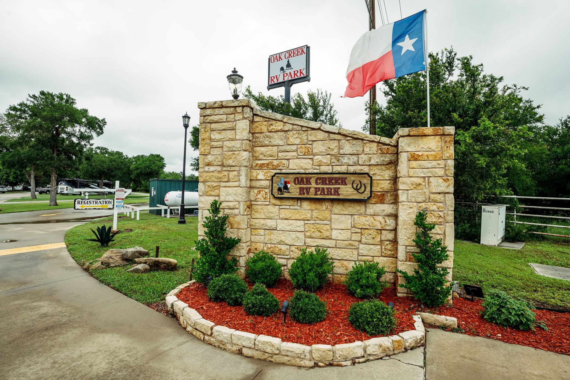 A stone sign with a texas flag and a red white and blue flag.