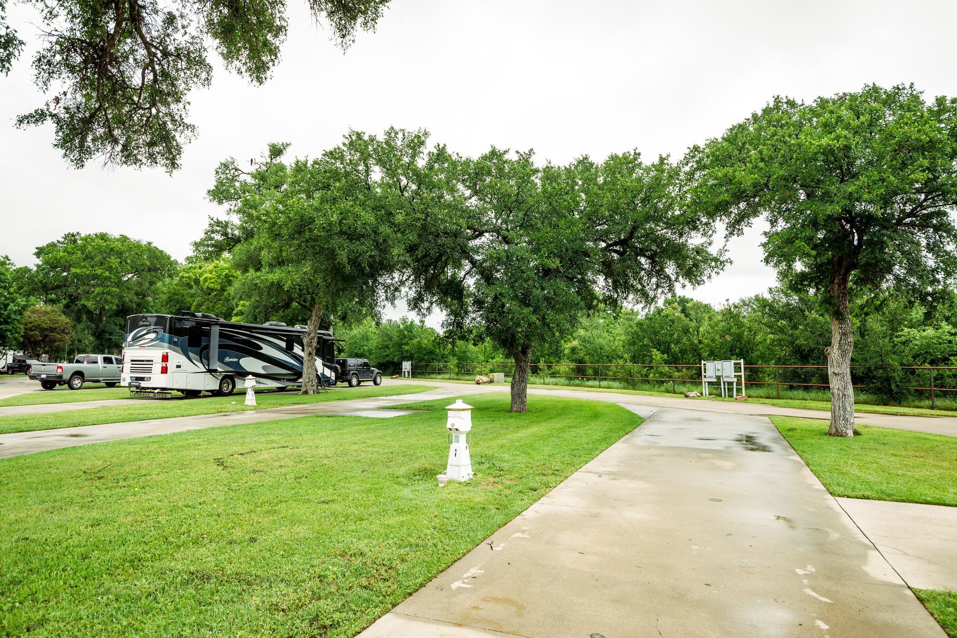 A rv is parked in a grassy area next to a concrete walkway.