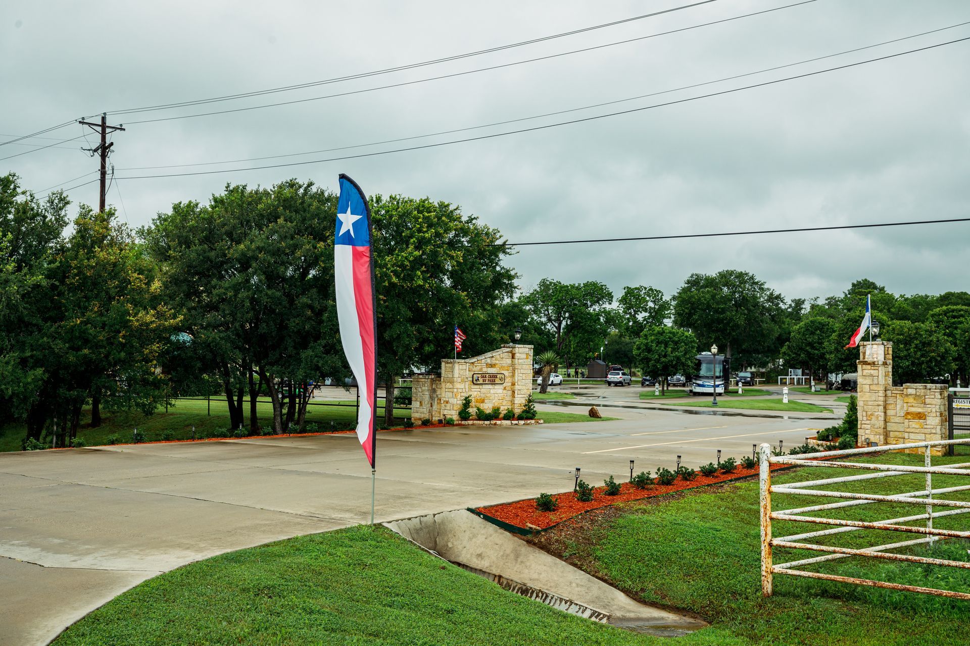 A red , white and blue flag is flying in front of a fence.