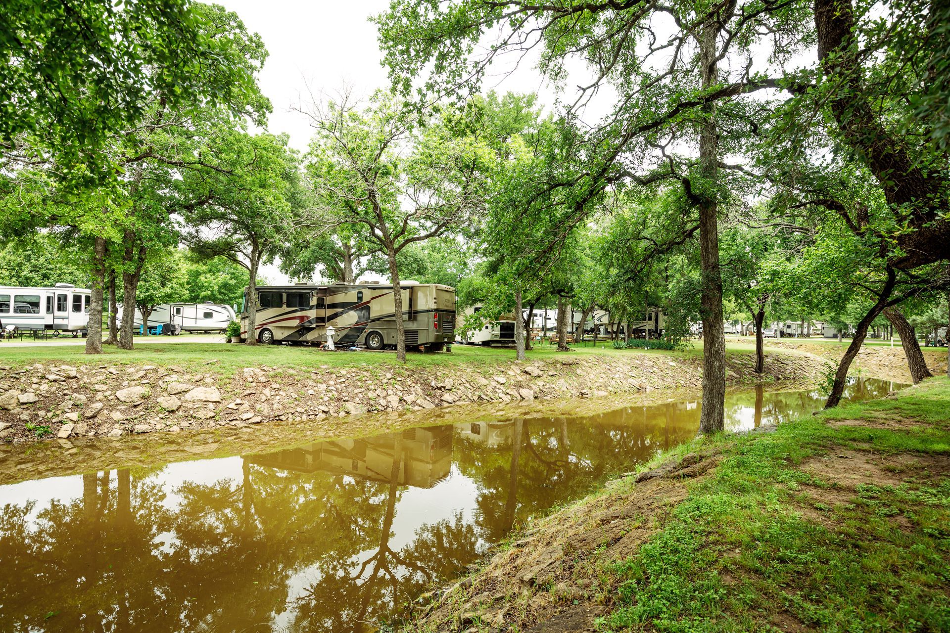A rv parked next to a river surrounded by trees.