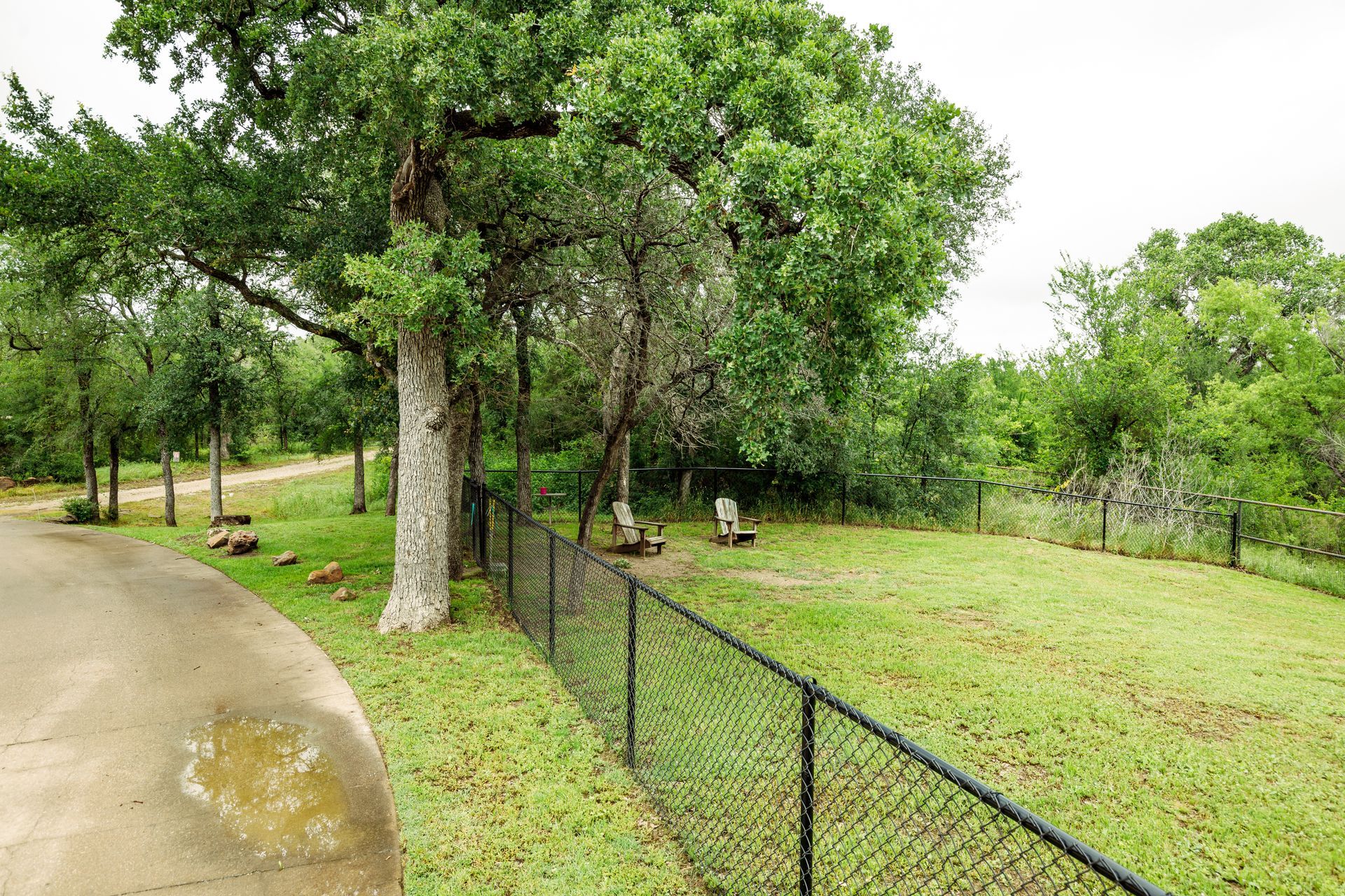 A chain link fence surrounds a picnic area in a park.