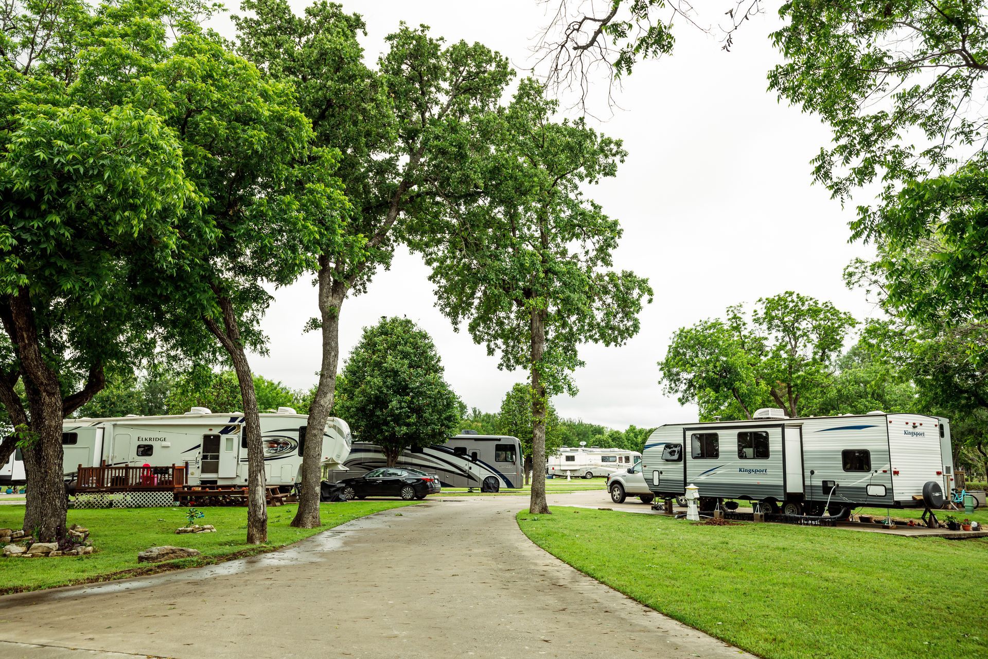 A row of rvs parked in a campground surrounded by trees.