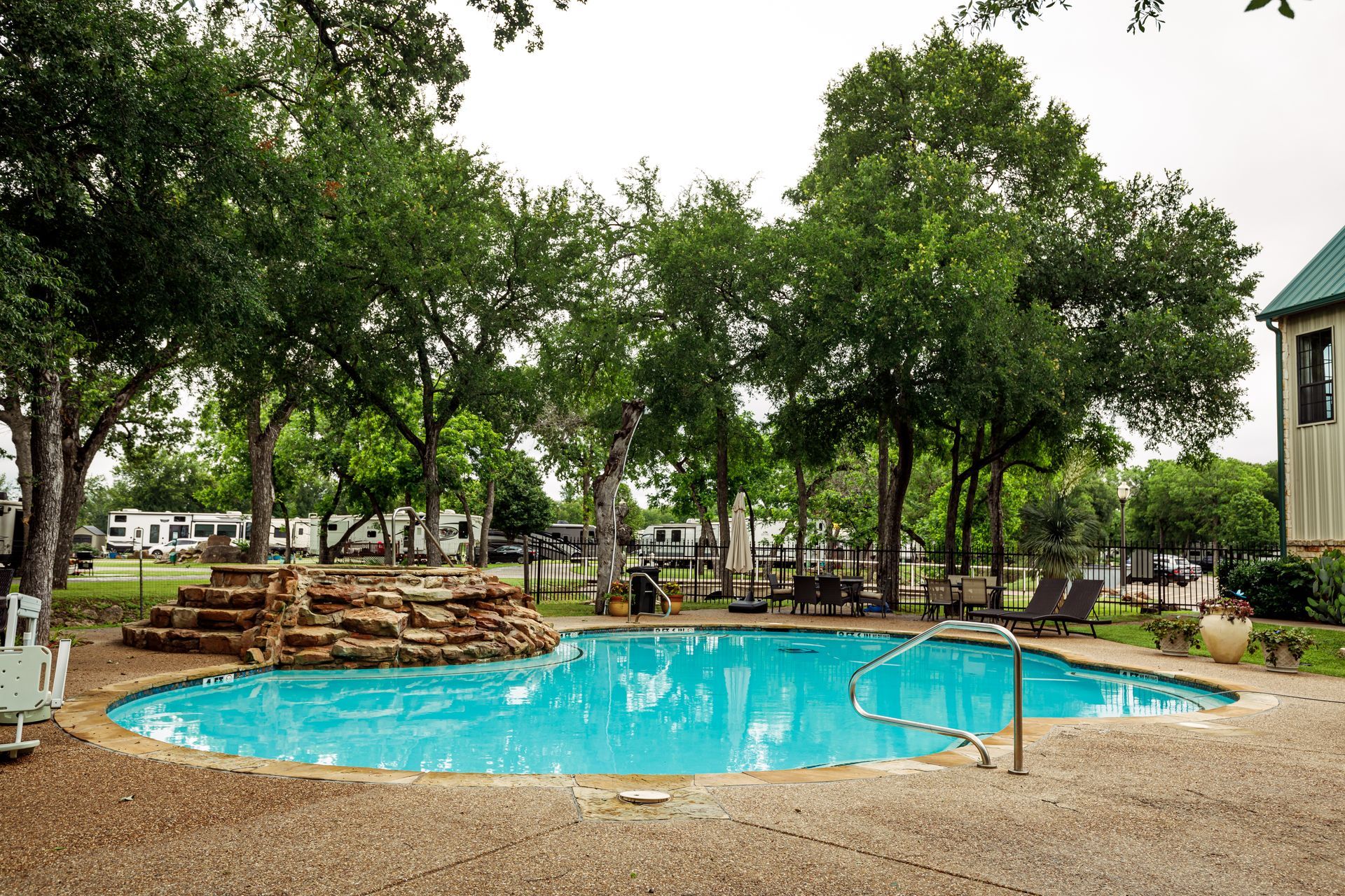 A large swimming pool is surrounded by trees and chairs.