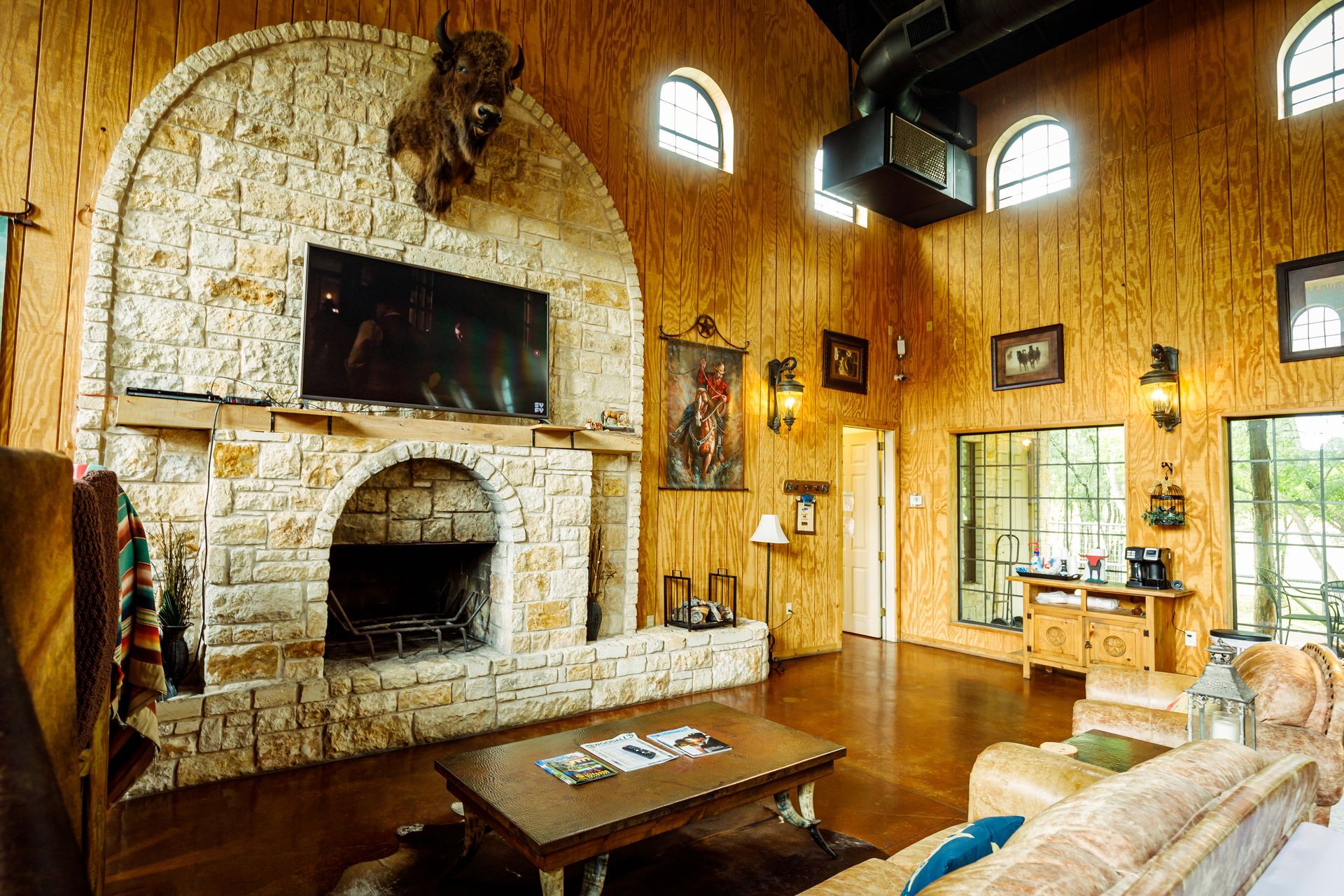 A living room with a stone fireplace and a flat screen tv.