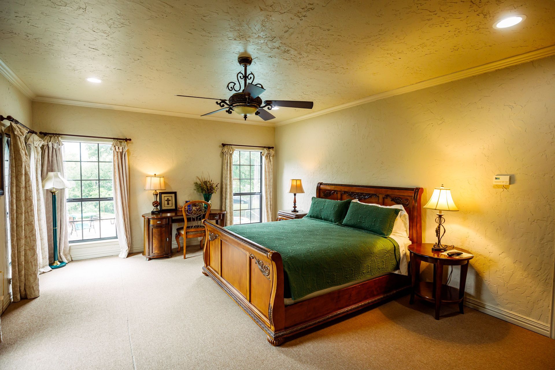 A bedroom with a king size bed and a ceiling fan.