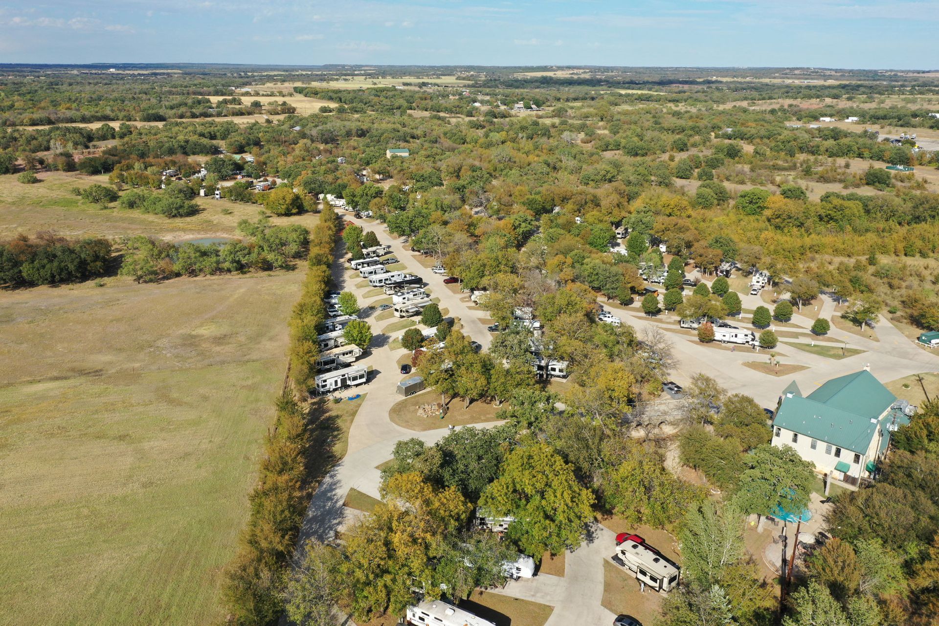 An aerial view of a park with a lot of trees and a green building.