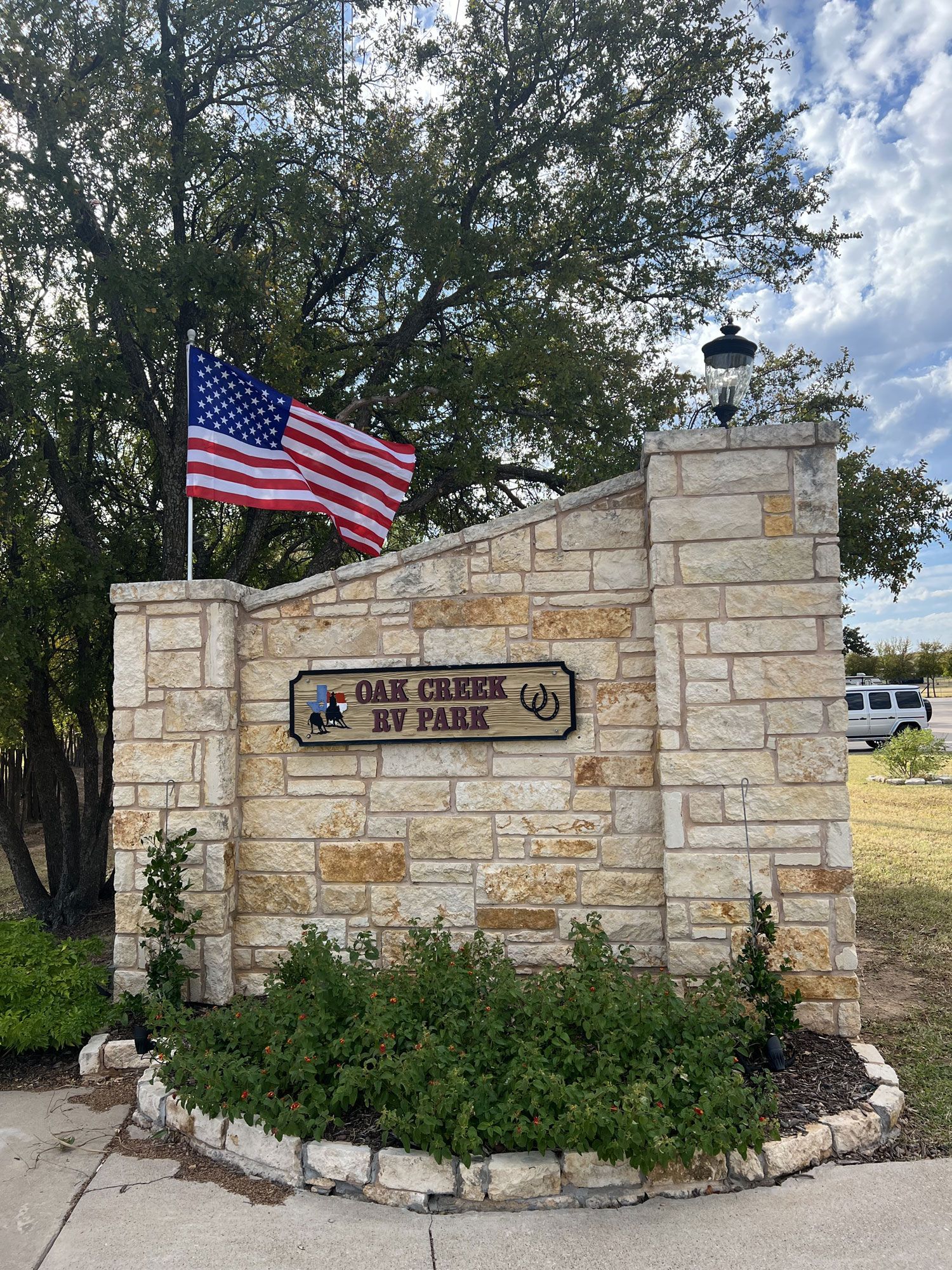 A brick wall with a sign that says `` oak creek rv park '' and an american flag.