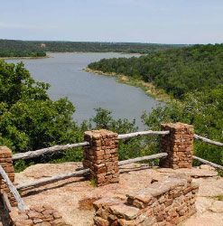 A view of a lake from a brick fence surrounded by trees.