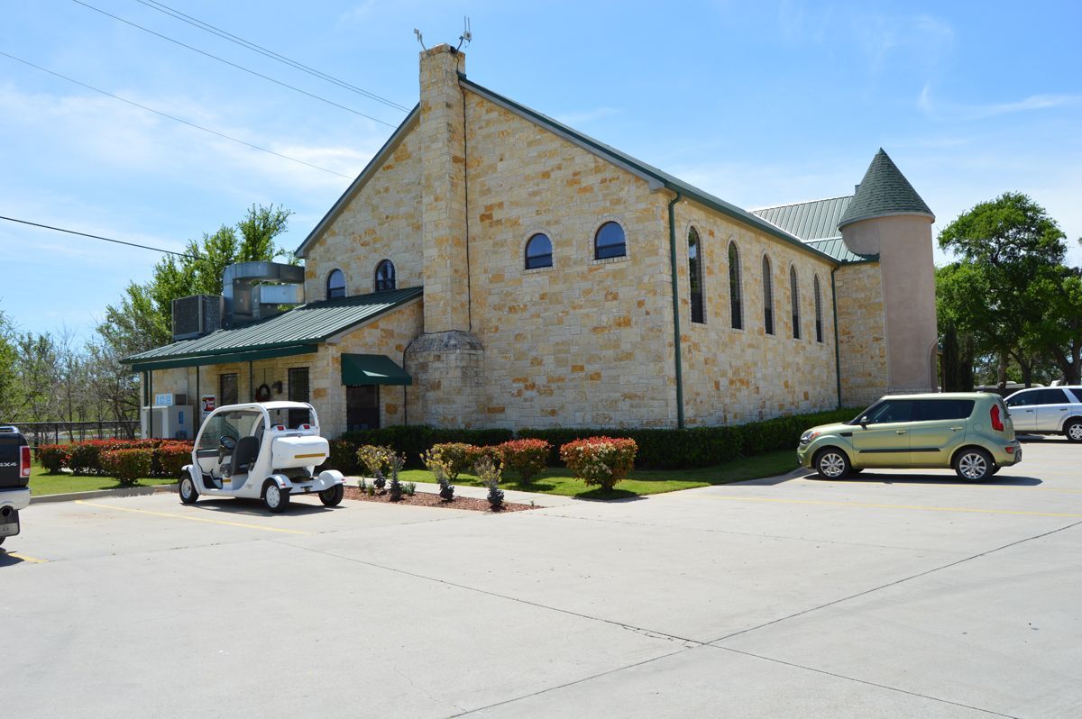 A golf cart is parked in front of a large stone building.