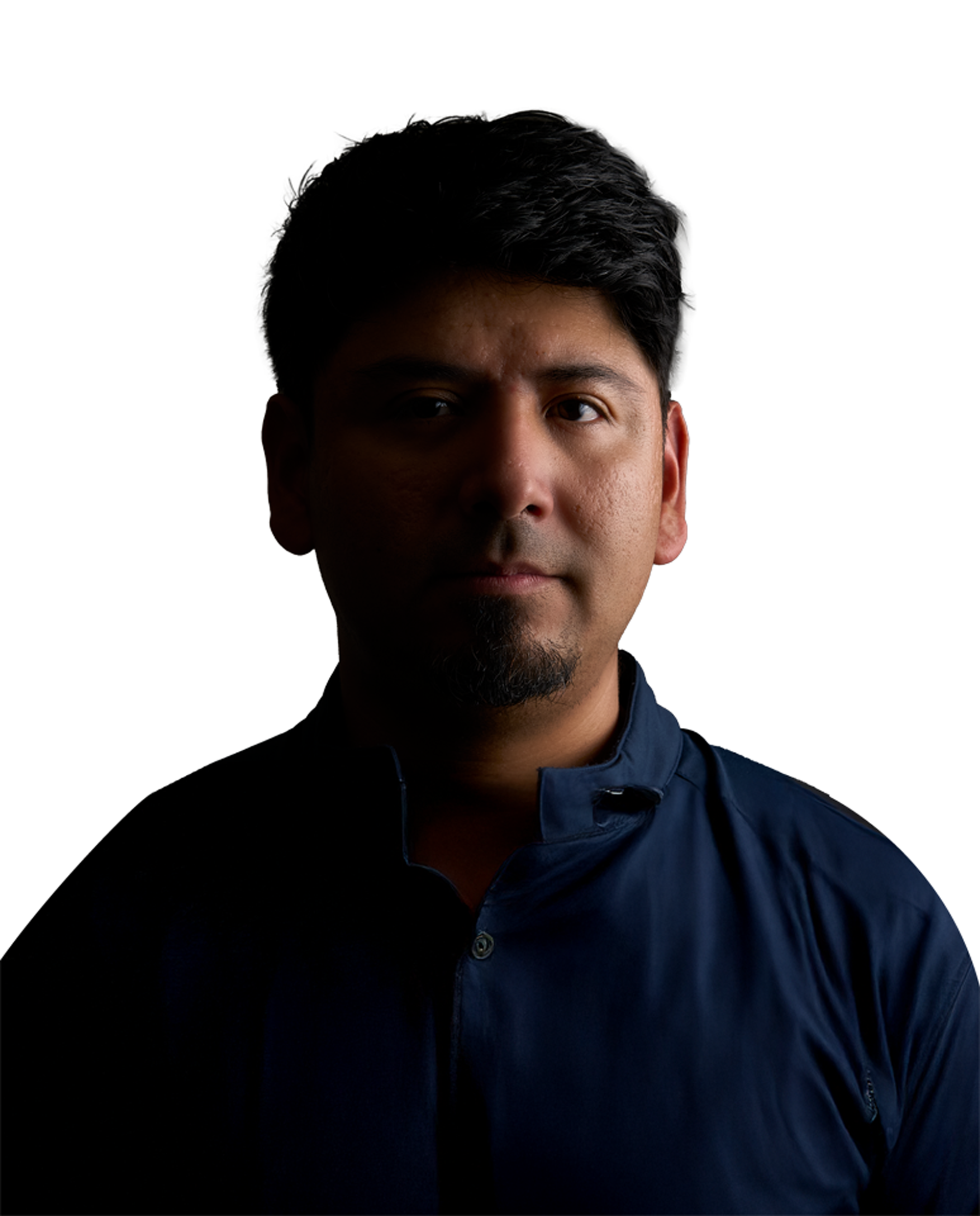A man in a blue shirt is standing in the dark