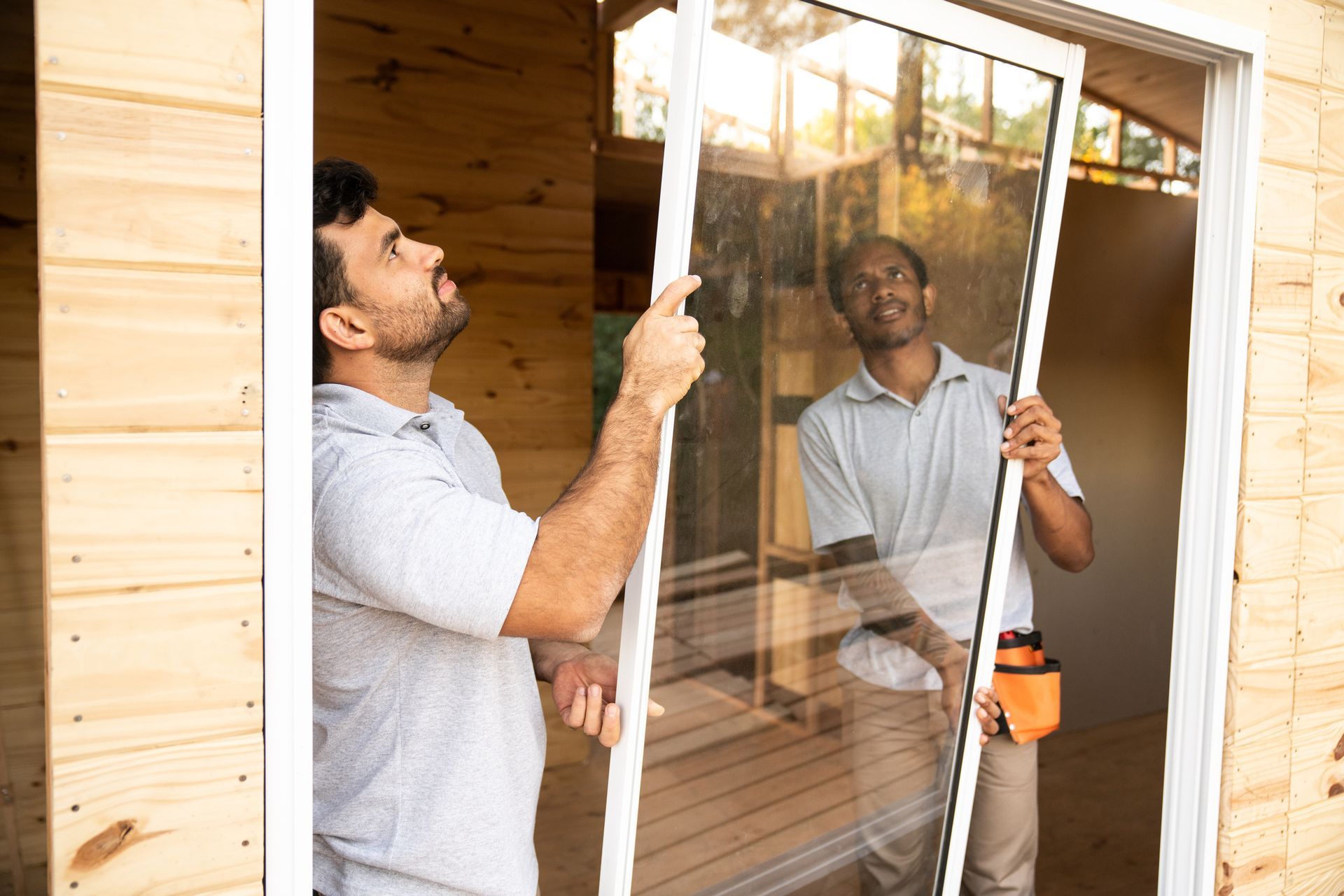 Construction workers installing windows on a wooden house.
