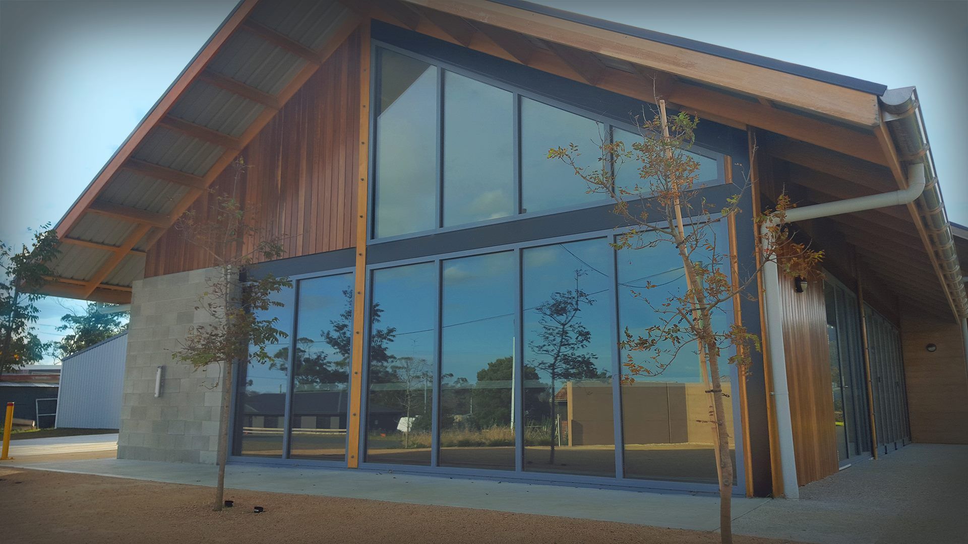 Modern building with large windows, brown wood accents, and a sloped roof.