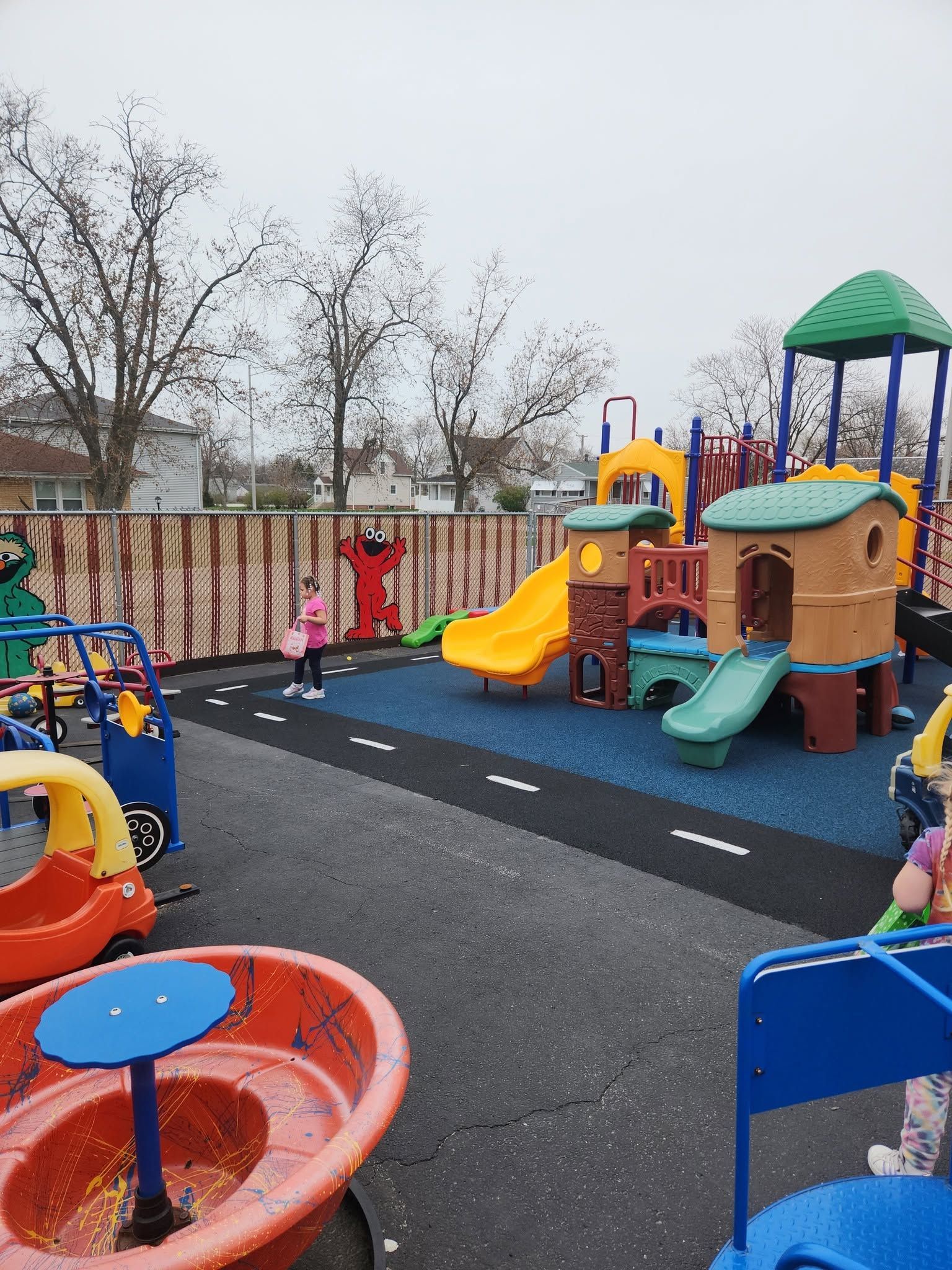 Colorful playground with slides, climbing structures, and play vehicles on a blacktop surface