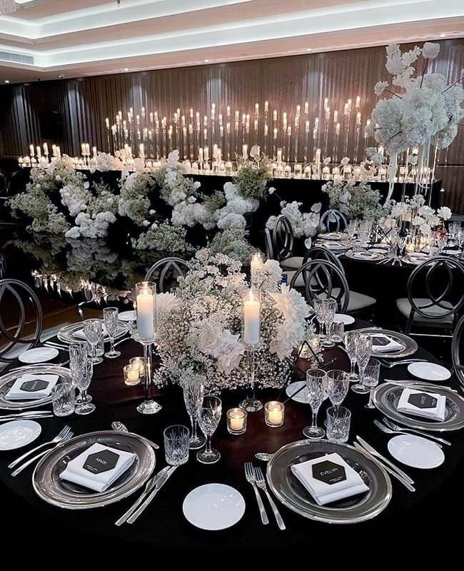 A table set for a wedding reception with plates , utensils , candles and flowers.