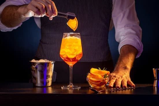 A bartender is pouring a drink into a glass with ice.