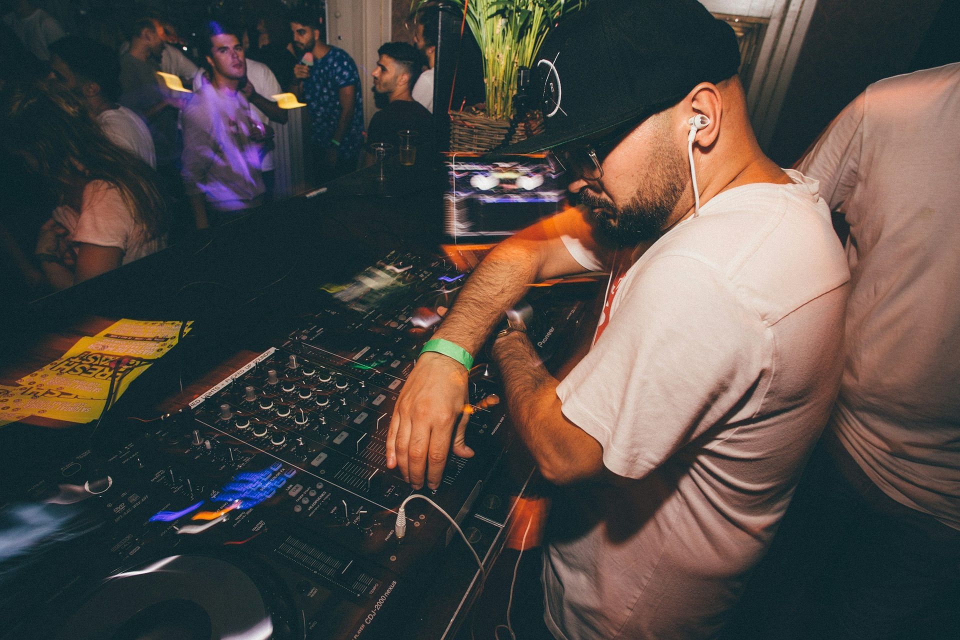 A man is sitting in front of a dj mixer at a party.